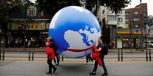 Menschen tragen einen riesigen Globus durch die Straßen von Seoul