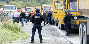 Ein Lkw-Stau, ein Polizist steht breitbeinig davor