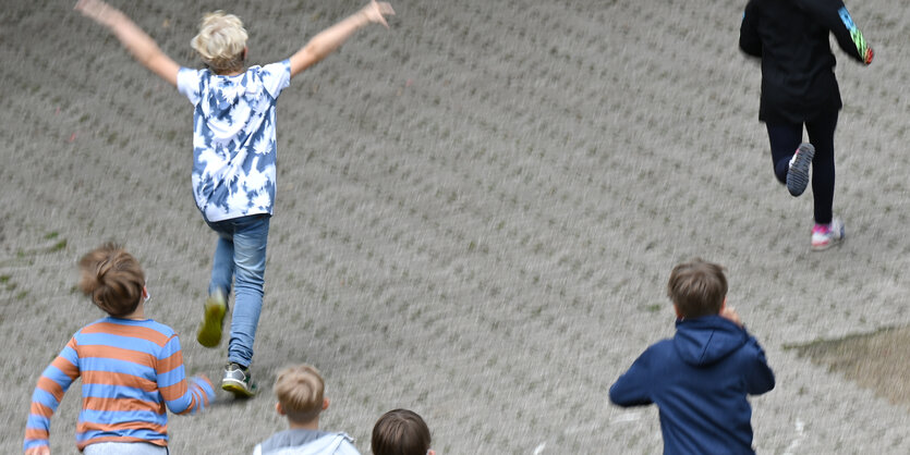 Kinder laufen über einen grauen Schulhof