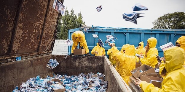 Aktivisten entsorgen AfD-Flyer in einem Müllcontainer