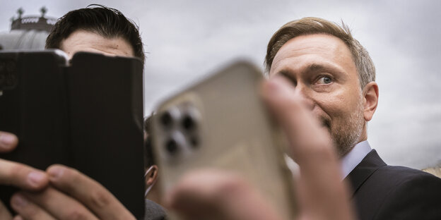 Hände mit IPhones strecken sich dem Politiker Christian Lindner entgegen