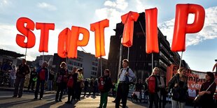 Menschen halten rote Buchstaben in die Höhe, man kann den SChriftzug "Stop TTIp" lesen