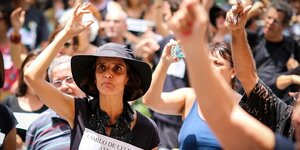 Demonstrierende recken die Hände, eine Frau trägt einen schwarzen Hut