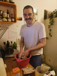 Ein Mann mit Schnurrbart steht in einer Küche und knetet Teig