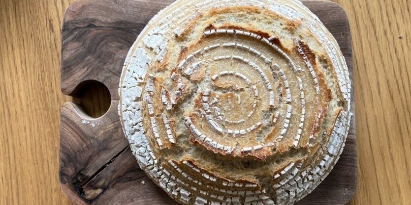 Ein frisch gebackenes Brot liegt auf einem Brett