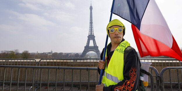 Ein Gelbwesten-Demonstrant in Paris mit dem Eiffelturm im Hintergrund.