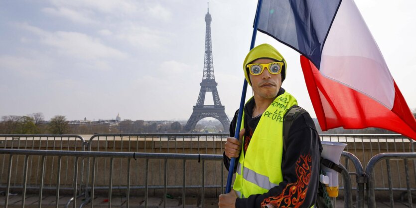 Ein Gelbwesten-Demonstrant in Paris mit dem Eiffelturm im Hintergrund.