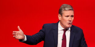 Keir Starmer redet vor rotem Hintergrund