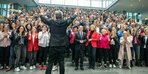 Ralf Mützenich steht mit dem Rücken zur Kamera vor einer Gruppe der SPD Franktion, die ihm applaudiert