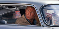 James Bond (Daniel Craig) sitzt kunstvoll verschrammt in einem verschrammten Bond-Mobil.