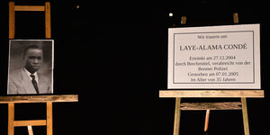 Auf zwei Staffeleien in der Nacht stehen ein Bild von Laye Condé und eine Gedenktafel