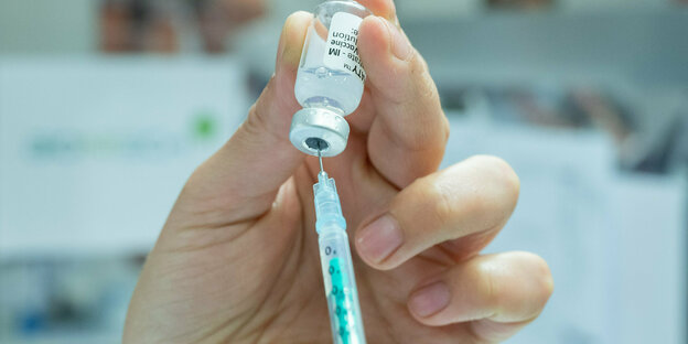 Eine Hand zieht eine Impfspritze auf