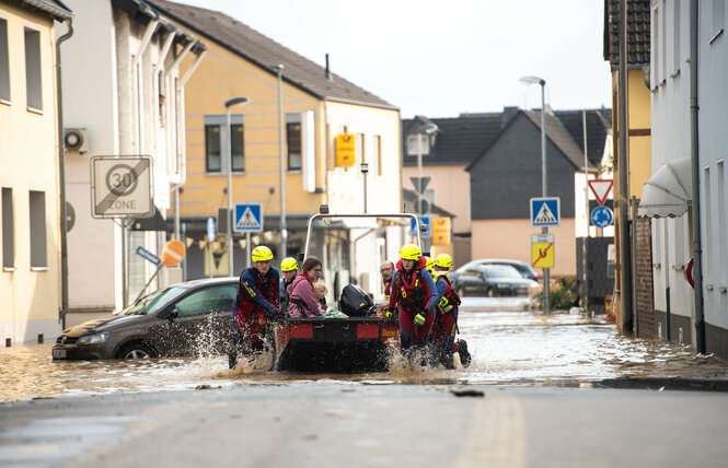 Eine überflutete Straße, Menschen werden auf einem Boot evakuiert