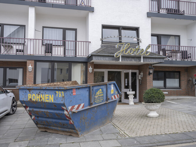 Ein Hotel, davor steht ein blauer Bauschutt-Container