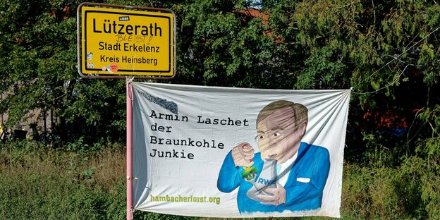 Plakat Laschet Braunkohlejunkie und Ortsschild von Lützerath