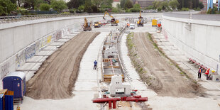 Bauarbeiter bringen auf der Baustelle der Erweiterung der A100 im Bezirk Neukölln den Untergrund für die Fahrbahnen auf