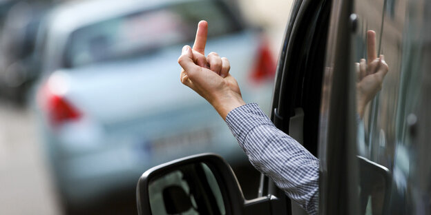 Autofahrere steckt den Mittelfinger aus dem Fahrerfenster raus