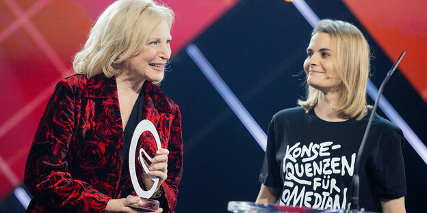 Maren Kroymann hält ihren Preis in der Hand, daneben steht Hazel Brugger in einem T-Shirt mit der Aufschrift "Konsequenzen für Comedian XY"