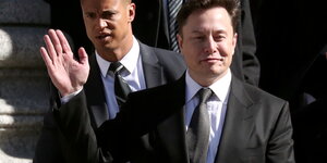 Elon Musk hebt die Hand zum Gruß