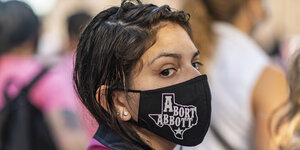 Eine Demonstrantin mit einem beschrifteten Mundnasenschutz