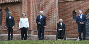 Fünf Spitzenpolitiker, unter anderem Merkel und Steinmeier, stehe vor einer Kirche in Halle