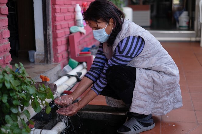 Frau beugt sich zu einer Wasserleitung hinunter