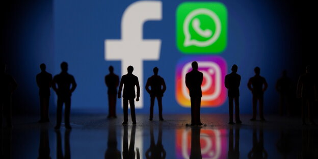 Eine Gruppe Figuren steht vor den Logos von Facebook, Whatsapp und Instagram