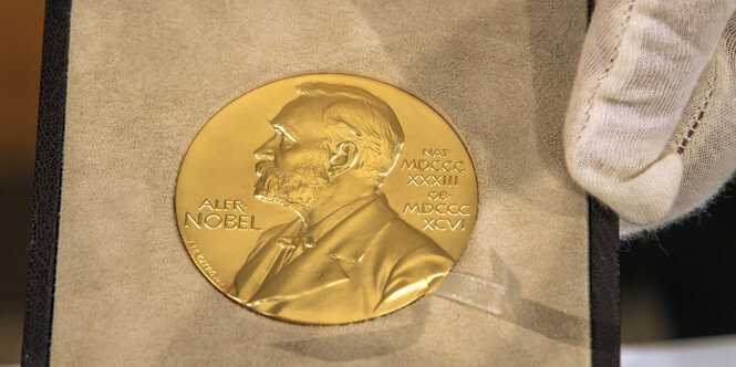 Eine Hand hält die goldene Nobelpreismedaille