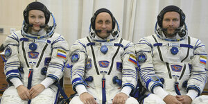 Drei Menschen in Raumfahrtanzügen.