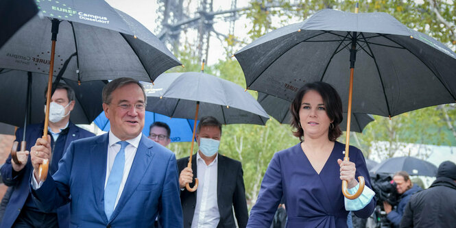 Laschet und Baerbock mit Regenschirmen.