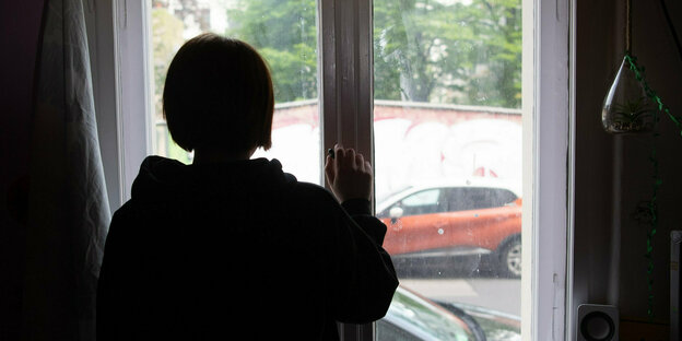 Eine Jugendliche steht am Fenster.