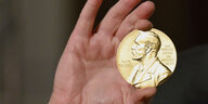 Eine Nobelmedaille wird während einer Zeremonie in New York hochgehalten.