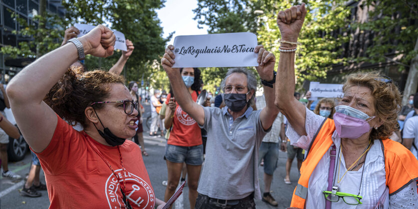 3 Frauen recken die Fäuste im Protest , ein Mann hält ein Schild