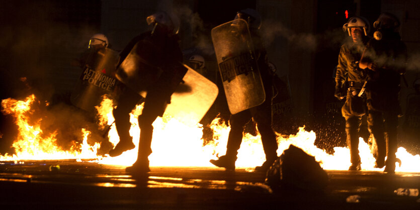 Polizisten stehen vor Flammen von Brandbomben