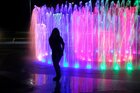 Eine Frau steht vor einem bunt beleuchtetem Springbrunnen