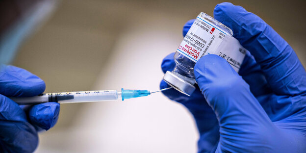 Eine Spritze wird mit Impfstoff aufgezogen.