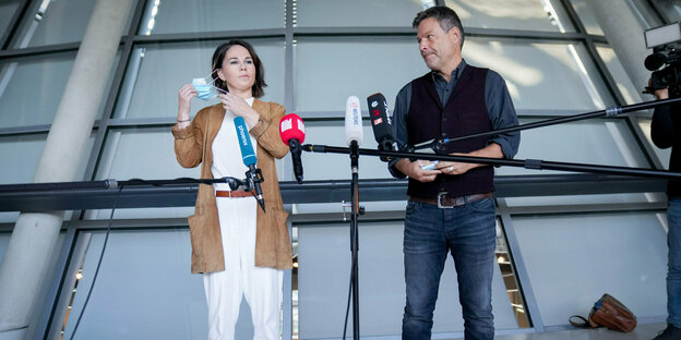 Annalena Baerbock und Robert Habeck stehen vor einem Mikrofon im Reichstag