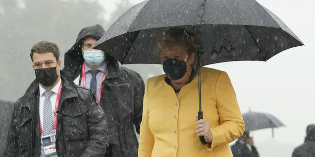 Angela Merkel mit Regenschirm im Regen.