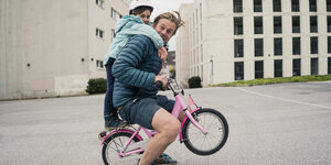 Vater und Tochter auf einem Kinderrad.
