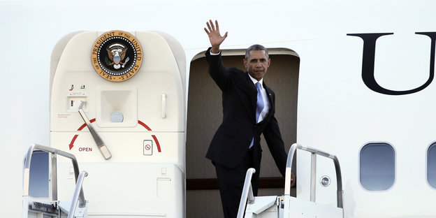 Obama winkt, während er das Flugzeug besteigt.