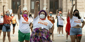 Eine Gruppe von Frauen demonstriert - den rechten Arm mit geballter Faust in dieHöhe gestreckt