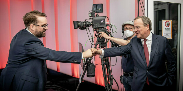 Paul Ronzheimer und Armin Laschet begrüßen sich in einem Fernsehstudio