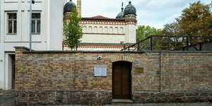 Eine Mauer mit einer Tür im Vordergrund, im Hintergrund ist die Synagoge zu sehen