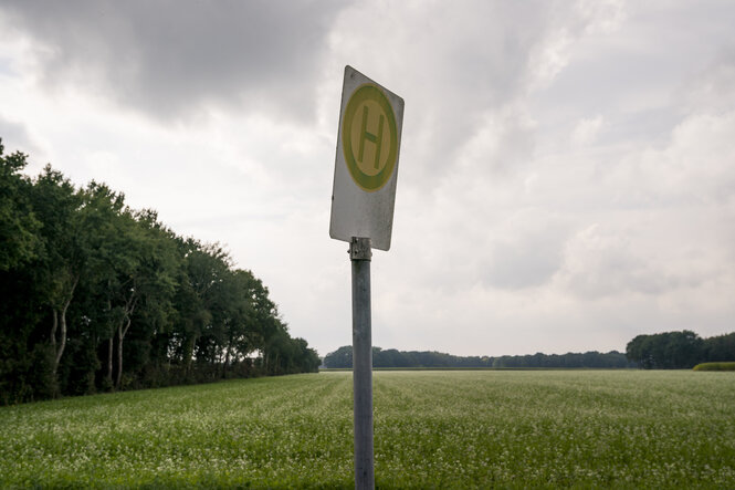 Einsames Bushaltestellenschild in weiter Landschaft