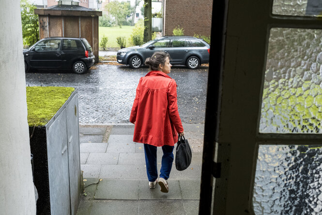 Blick aus einer Haustür auf Frau, die Haus gerade verlassen hat