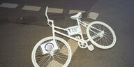 Weisses Fahrrad liegend auf einer nächtlichen Straße