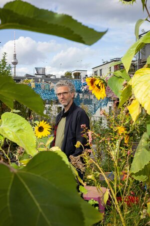 Johannes von Gwinner auf der Gemeinschaftsterrasse des Hauses hinter Sonnenblumen Johannes von Gwinner auf der Gemeinschaftsterrasse des Hauses hinter Sonnenblumen