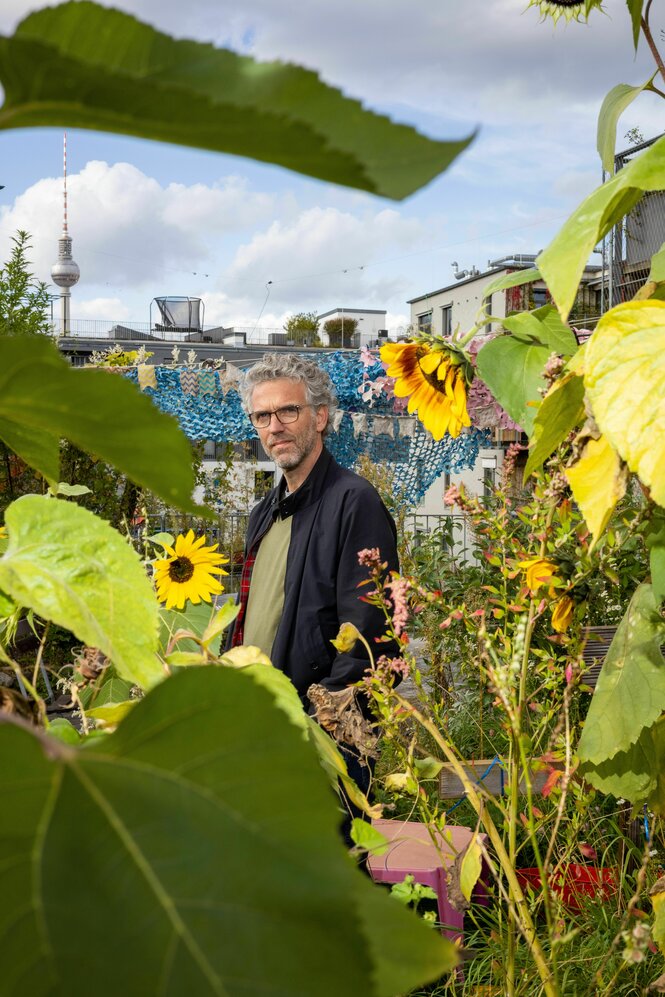 Johannes von Gwinner auf der Gemeinschaftsterrasse des Hauses hinter Sonnenblumen