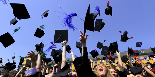 Absolventen werfen ihre Hüte in die Luft