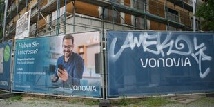 Ein Bauszaun mit Werbeplakat vor einer Baustelle.